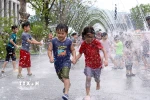 Các em nhỏ chơi đùa bên đài phun nước để tránh nóng tại Seoul, Hàn Quốc. (Ảnh: THX/TTXVN)