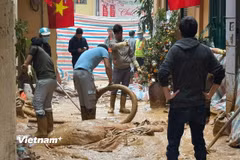 Người dân và công nhân được huy động nhằm khắc phục sự cố tràn bùn. (Ảnh: Minh Hiếu/Vietnam+)