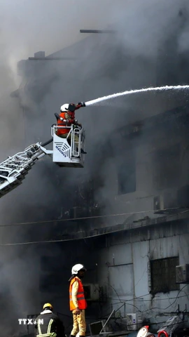 Lính cứu hỏa nỗ lực dập lửa vụ cháy tòa nhà Trung tâm thương mại ở Karachi, Pakistan ngày 18/1/2026. (Ảnh: THX/TTXVN)