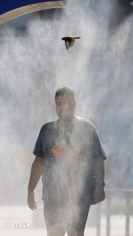 Một người đàn ông làm mát tại thiết bị phun nước ở Bucharest, Romania. (Nguồn: THX/TTXVN)
