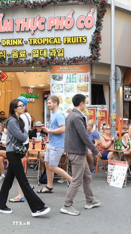 Khách du lịch nước ngoài thưởng thực ẩm thực tại phố Tạ Hiện, Hà Nội. (Ảnh: Hoàng Hiếu/TTXVN)