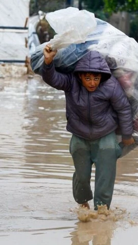 Một người Palestine tị nạn mang theo đồ đạc trong một trại lều bị ngập lụt ở Nuseirat, trung tâm Dải Gaza, ngày 12/12. (Ảnh: Reuters)
