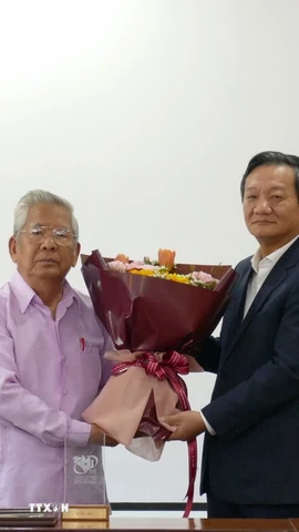 Đại sứ Việt Nam tại Lào Nguyễn Minh Tâm tặng hoa chúc mừng Nghệ sỹ Quốc gia-nhạc sỹ Lào Douangmixay Likaya. (Ảnh: Xuân Tú/TTXVN)