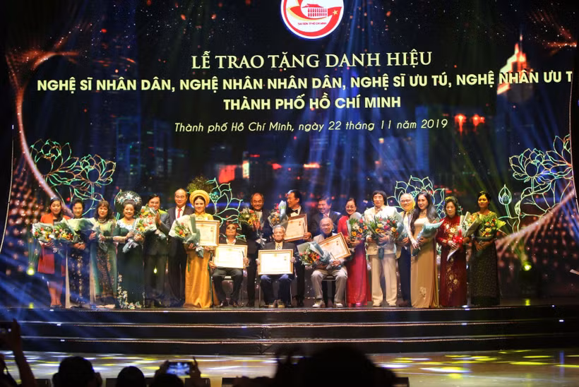 Bí thư Thành ủy Nguyễn Thiện Nhân và Chủ tịch Ủy ban Nhân dân Thành phố Nguyễn Thành Phong với các nghệ sỹ nhân dân được vinh danh. (Ảnh: Thanh Vũ/TTXVN)