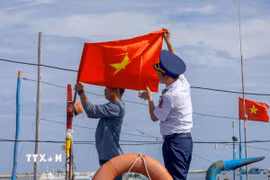 Lá cờ Tổ quốc mới được cán bộ Bộ Tư lệnh Vùng Cảnh sát biển 2 thay trên tàu cá của ngư dân trước chuyến vươn khơi, tiếp thêm niềm tin để bà con yên tâm bám biển, bám ngư trường. (Ảnh: Xuân Quý/TTXVN)