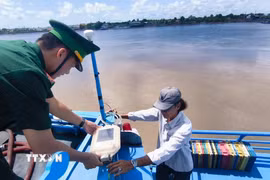 Thiếu tá Phan Minh Vương, Trạm trưởng Trạm Kiểm soát Biên phòng Gành Hào (Bộ đội Biên phòng tỉnh Cà Mau), cùng ngư dân kiểm tra tín hiệu hệ thống VMS trên tàu của ngư dân, đảm bảo hoạt động hiệu quả và ổn định. (Ảnh: Chanh Đa/TTXVN)