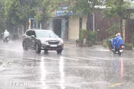 Người dân đi lại trong mưa lớn. (Ảnh: Nguyên Lý/TTXVN)