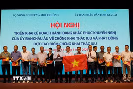 Thứ trưởng Bộ Nông nghiệp và Môi trường Võ Văn Hưng trao quà và cờ tổ quốc cho ngư dân. (Ảnh: Đình Quân/TTXVN)