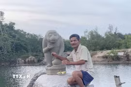 Ông Dương Đình Lục và tượng Khỉ Hanuman do ông trục vớt được. (Ảnh: TTXVN phát)