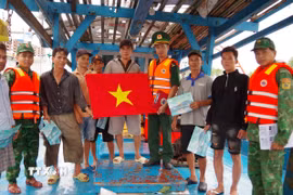 Trạm Kiểm soát Biên phòng Vàm Láng tuyên truyền về phòng chống khai thác IUU và tặng cờ Tổ quốc cho thuyền trưởng và ngư dân. (Ảnh: Công Trí/TTXVN)