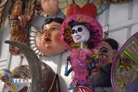 Một mô hình Catrina-người phụ nữ với chiếc mũ rộng vành, váy áo lộng lẫy và gương mặt hóa trang thành hộp sọ trong một quầy bánh Pan de muerto tại thủ đô Mexico City, Mexico. (Ảnh: Phi Hùng/TTXVN)