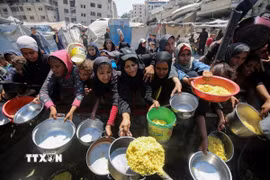 Người dân chờ được phát thực phẩm cứu trợ tại Gaza. (Ảnh: THX/TTXVN)