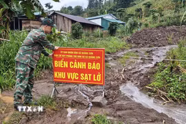 Lực lượng chức năng xã Quảng Sơn căng dây, cắm biển cảnh báo tại khu vực sạt lở ở thôn Đắk Snao. (Ảnh: Nguyễn Huy Thành/TTXVN)