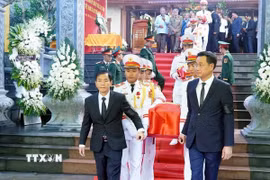 Đại biểu thực hiện nghi thức di quan để an táng các hài cốt các liệt sỹ. (Ảnh: TTXVN phát)