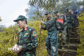 Trên cung đường núi hiểm trở, chiến sỹ cõng hài cốt liệt sỹ xuống núi sau khi hoàn thành công tác quy tập tại bản Lồng, xã Quài Tở, tỉnh Điện Biên. (Ảnh: Xuân Tư/TTXVN)