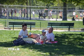 Một gia đình tránh nóng dưới bóng mát trong một công viên ở thủ đô Paris. (Ảnh: Hữu Chiến/TTXVN)