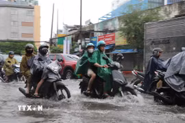 Người dân di chuyển qua đoạn đường Đinh Bộ Lĩnh, phường Bình Thạnh bị ngập do cơn mưa chiều 23/9. (Ảnh: Hồng Đạt/TTXVN)