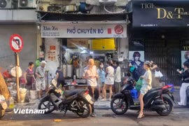 Hàng dài người xếp hàng chờ đến lượt tại một quán phở vào sáng sớm. (Nguồn: Vietnam+)