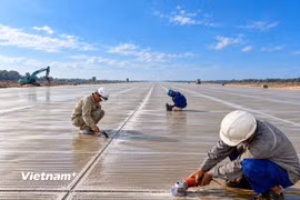 Công nhân thi công mài, cắt tạo rãnh kháng trượt để hoàn thiện đường cất hạ cánh. (Ảnh: Anh Chiến/Vietnam+)