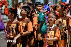 Các em nhỏ tham gia đoàn rước với những mô hình ngựa giấy nhiều màu sắc, tái hiện nét vui chơi dân gian trong đêm Trung thu giữa lòng Hà Nội. (Ảnh: Phạm Tuấn Anh/TTXVN)