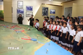 Học sinh trường Dongsavanh, huyện Sepon (Savannakhet, Lào) tham quan sa bàn ghi lại các trận đánh ác liệt của Liên minh chiến đấu Việt Nam-Lào. (Ảnh: Xuân Tú/TTXVN)