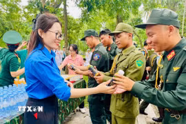 Tình nguyện viên trao nước uống cho các lực lượng làm nhiệm vụ. (Ảnh: TTXVN phát)