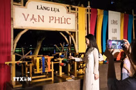 Người dân chụp ảnh lưu lại khoảnh khắc tại gian trưng bày của Làng lụa Vạn Phúc. (Ảnh: Khánh Hòa/TTXVN)