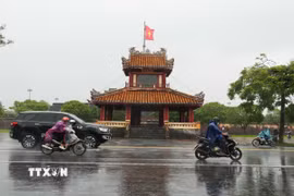 Các phương tiện di chuyển trong mưa lớn ở trước di tích Phu Văn Lâu, trung tâm thành phố Huế. (Ảnh: Nguyên Lý/TTXVN)