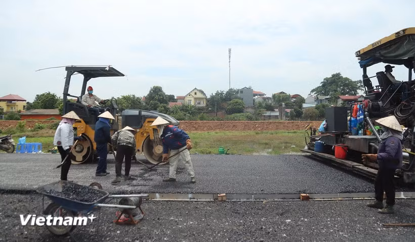 Nhà thầu thi công thảm nhựa nền đường một dự án đường bộ cao tốc. (Ảnh: Việt Hùng/Vietnam+)