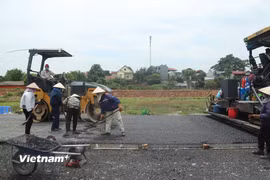 Nhà thầu thi công thảm nhựa nền đường một dự án đường bộ cao tốc. (Ảnh: Việt Hùng/Vietnam+)