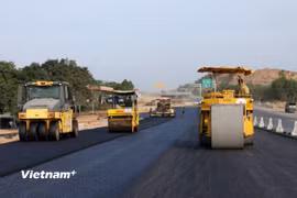Nhà thầu huy động máy móc, nhân lực để thảm những bê tông nhựa dự án cao tốc. (Ảnh: Khánh Hùng/Vietnam+)