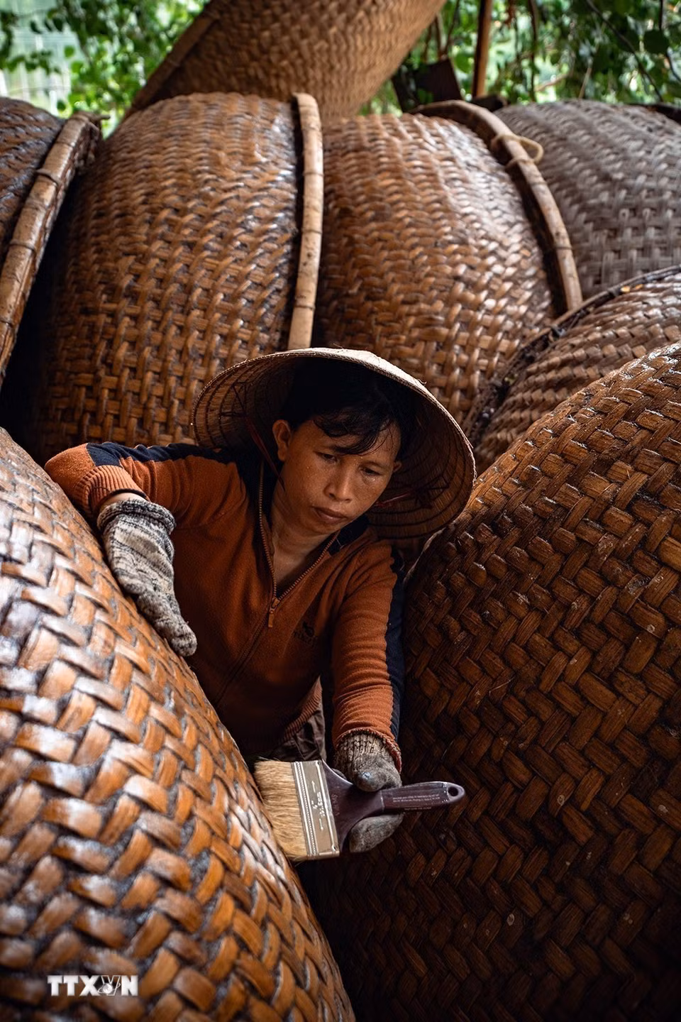 Người thợ thực hiện công đoạn quét dầu rái cho thúng chai.(Ảnh: Khánh Hòa/TTXVN)