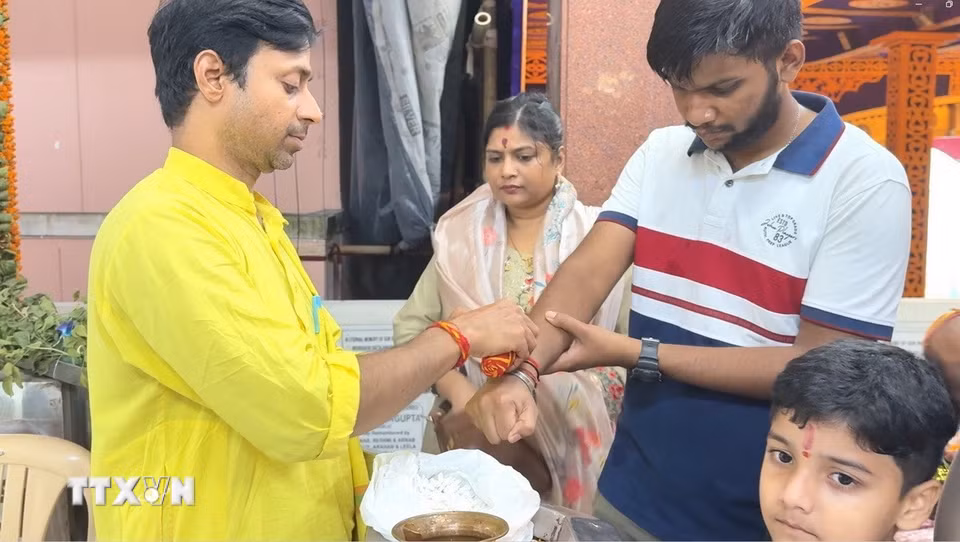 Giáo sỹ cột sợi chỉ kalava linh thiêng để ban phước lành và may mắn cho tín đồ đạo Hindu. (Ảnh: Ngọc Thúy/TTXVN)