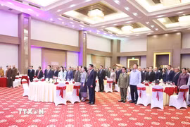 Các đại biểu tham dự Tiệc chiêu đãi thực hiện nghi lễ Chào cờ. (Ảnh: Xuân Tú/TTXVN)