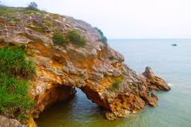 Nhìn từ trên cao, khu vực hang Mũi Trâu như một khuôn mặt người đang nhìn ra biển, cửa hang ngập trong nước khi thủy triều dâng cao. (Ảnh: Xuân Tiến/TTXVN)