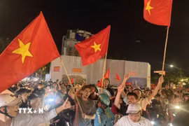 Người dân mang theo cờ Tổ quốc diễu hành trên các tuyến phố Hà Nội để mừng chiến thắng. (Ảnh: An Đăng/TTXVN)