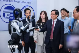 Phó Thủ tướng Hồ Quốc Dũng và các đại biểu tham quan robot tại Trung tâm thực hành tập trung của Trường Đại học Công nghệ. (Ảnh: Hoàng Hiếu/TTXVN)