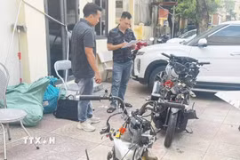Lực lượng chức năng đang khám nghiệm xe môtô trong vụ tai nạn. (Ảnh: Mạnh Tú/TTXVN