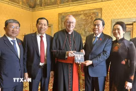Chủ tịch Quốc hội Trần Thanh Mẫn và Phu nhân chụp ảnh chung với Thủ tướng Tòa thánh Vatican, Hồng y Pietro Parolin và trao đổi tặng phẩm. (Ảnh: TTXVN)