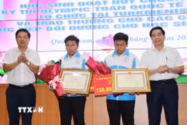 Bí thư Tỉnh ủy Quảng Nam Lương Nguyễn Minh Triết và Chủ tịch Ủy ban Nhân dân tỉnh Quảng Nam Lê Văn Dũng tặng Bằng khen và hoa cho hai anh em Nguyễn Trí Hiền và Nguyễn Trí Hậu. (Ảnh: Đoàn Hữu Trung/TTXVN)