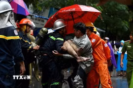 Lực lượng cứu hỏa đưa nạn nhân cuối cùng ra khỏi đám cháy tòa nhà 5 tầng ở số 8, ngõ 12, phố Núi Trúc, quận Ba Đình, Hà Nội. (Ảnh: Dương Giang/TTXVN)