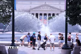 Du khách tránh nắng nóng bên đài phun nước tại khu vực National Mall (Quảng trường Quốc gia) ở thủ đô Washington D.C. (Ảnh: Ngọc Quang/TTXVN)