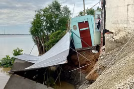 Một phần căn nhà và khu vực chứa vật liệu xây dựng bị sạt lở, sụp xuống sông sau sự cố xảy ra vào đêm 27/7/2026. (nh: TTXVN phát)