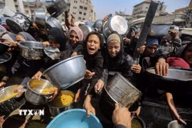 Người tị nạn Palestine nhận thức ăn cứu trợ tại thành phố Gaza. (Ảnh: THX/TTXVN)