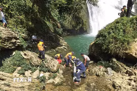 Lực lượng cứu nạn đưa thi thể nạn nhân lên khỏi khu vực chân thác Khâu Làn. (Ảnh: TTXVN phát)