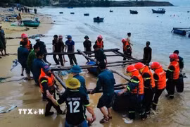 Lực lượng vũ trang tỉnh Đắk Lắk và chính quyền địa phương giúp dân cẩu kéo các tàu, bè nuôi trồng thủy sản lên khu vực an toàn. (Ảnh: TTXVN phát)