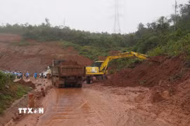 Lực lượng chức năng đang khẩn trương xử lý các điểm sạt lở trên Quốc lộ 24. (Ảnh: Dư Toán/TTXVN)