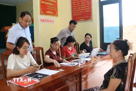 Cán bộ tiếp nhận, kiểm tra hồ sơ, thông tin liên quan đến đất đai của người dân. (Ảnh: Đồng Thúy/TTXVN)