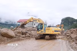 Các phương tiện máy móc tập trung san gạt cây cối, đất đá góp phần thông đường tạm thời cho nhân dân đi lại. (Ảnh: Quý Trung/TTXVN)