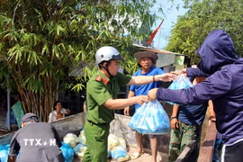 Lực lượng tại chỗ phối hợp với các nhóm thiện nguyện phân phối thức ăn cho các người dân vùng ngập Hàm Thắng. (Ảnh: Hồng Hiếu/TTXVN)